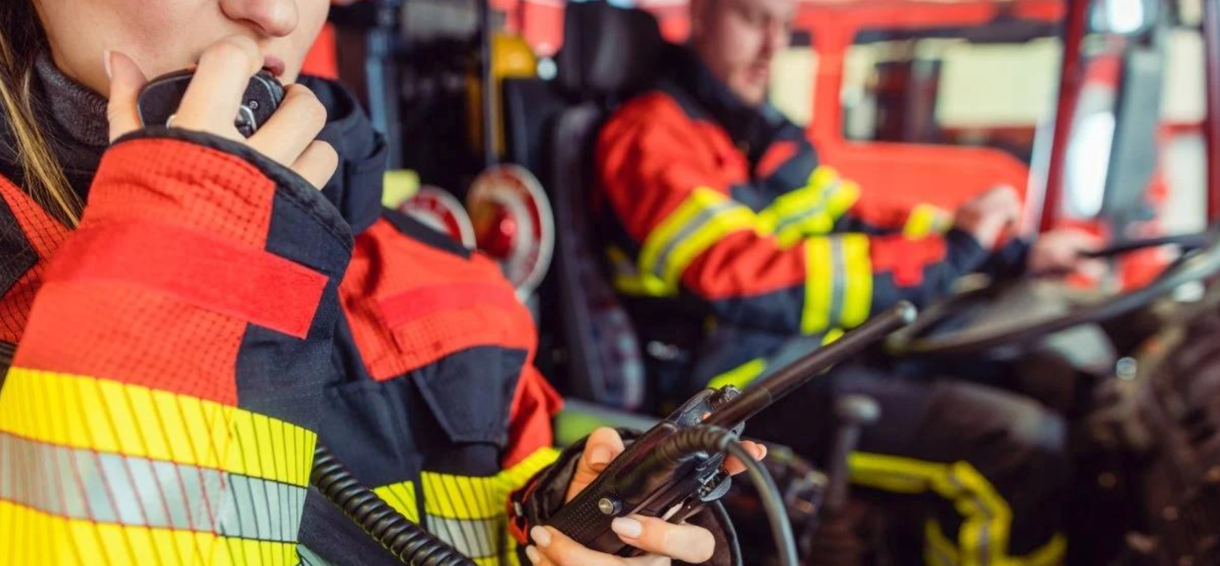 A firefighter is talking on a walkie talkie in a fire truck.