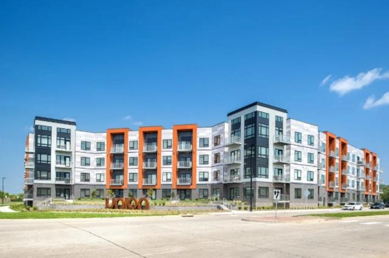 A large apartment building with a lot of windows and balconies on a sunny day.