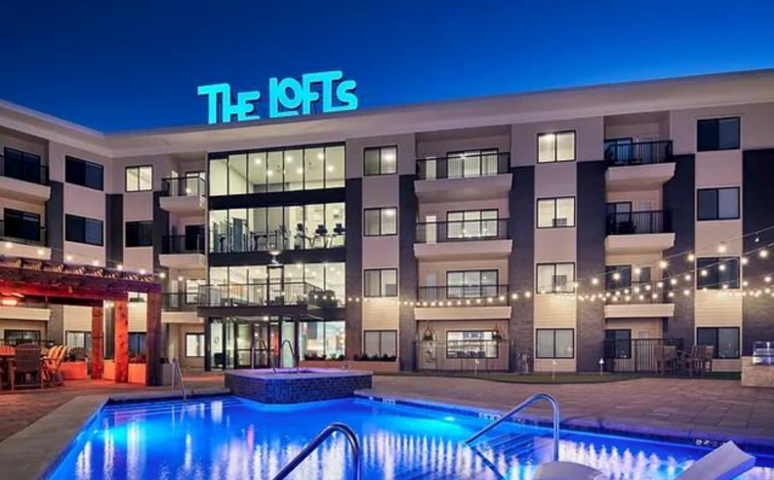 A large building with a pool in front of it that says the lofts