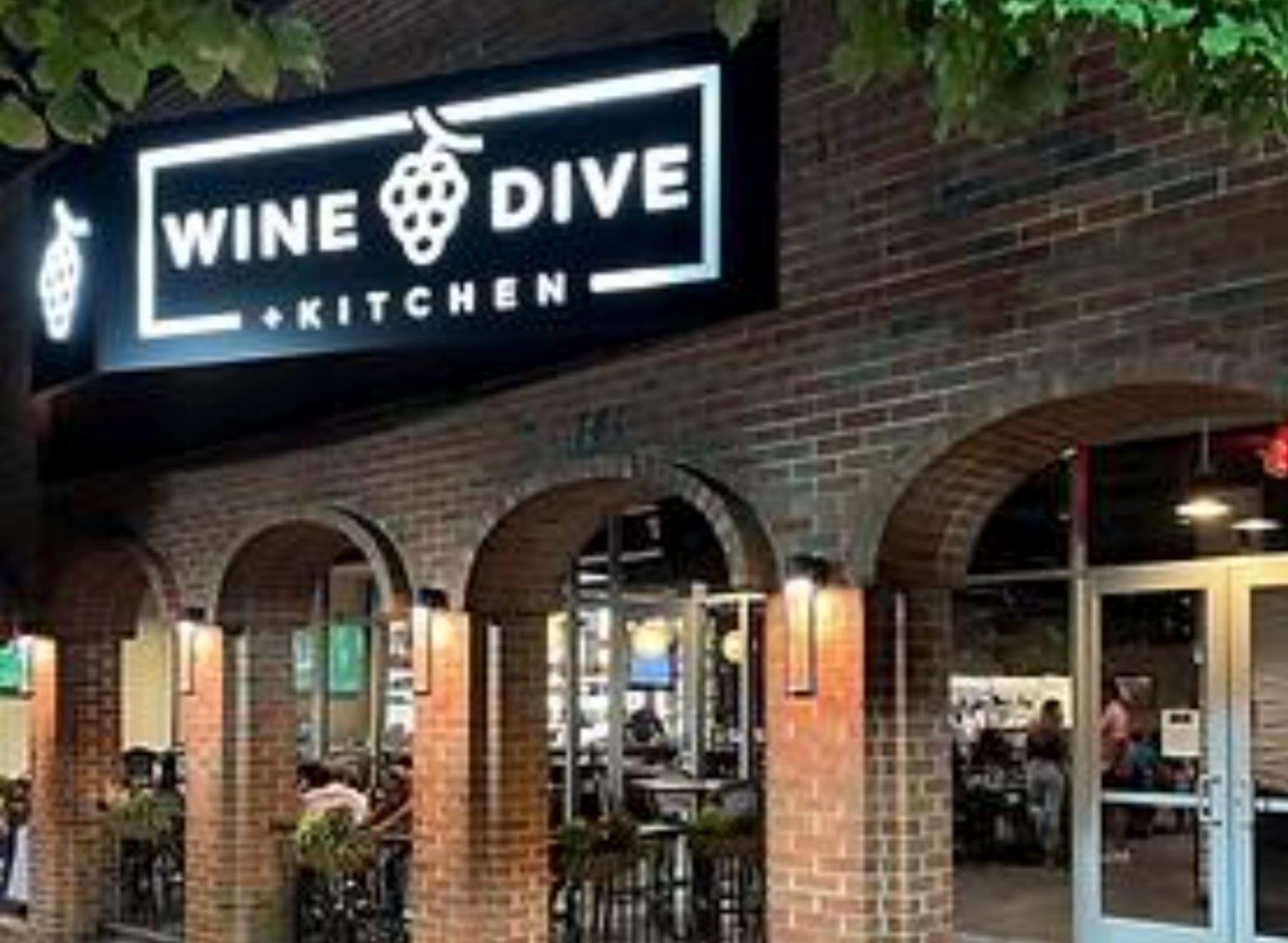 A restaurant called wine dive kitchen is located in a brick building.