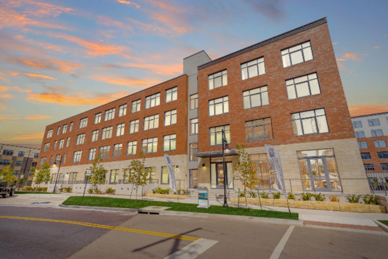 A large brick building with a lot of windows and a parking lot in front of it.
