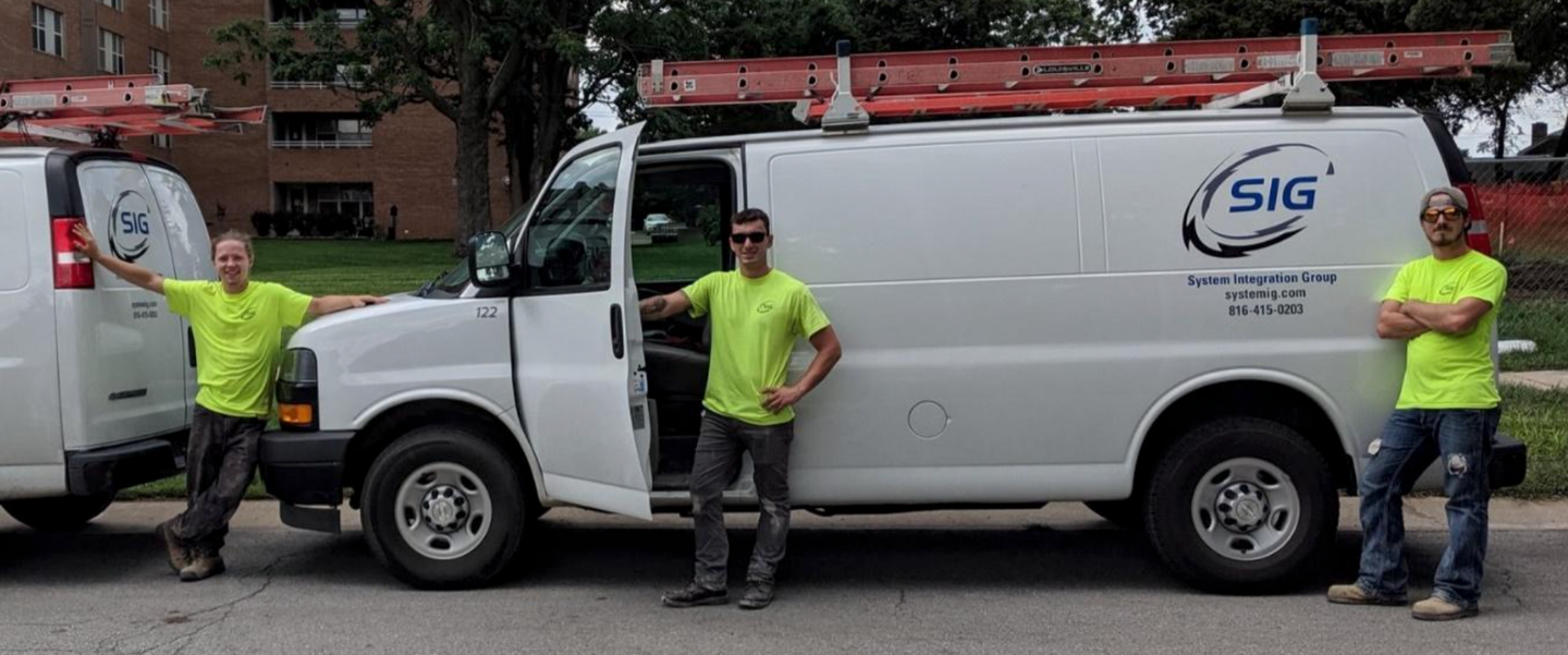 Three men are standing in front of a sig van