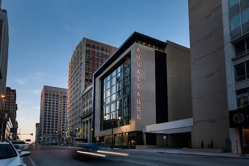 A car is driving down a city street in front of a large building.