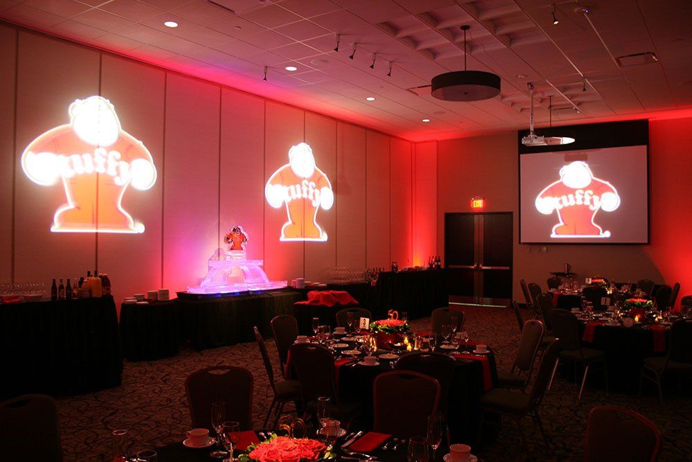 a room filled with tables and chairs with a puffy logo projected on the wall