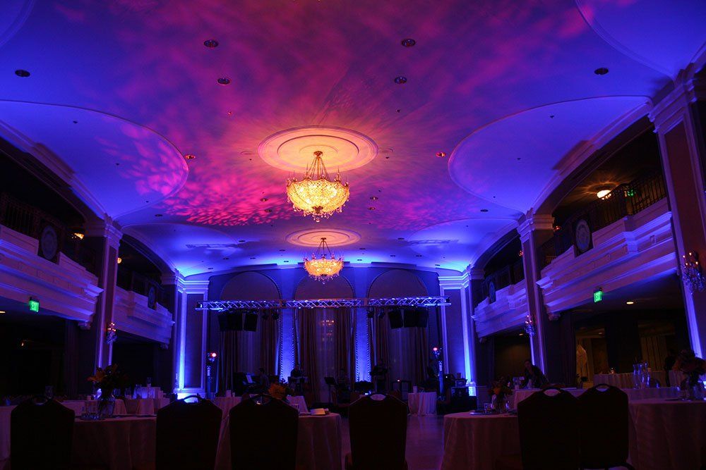 a large room with tables and chairs and a chandelier hanging from the ceiling