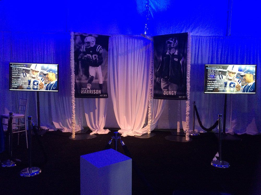 three televisions are displayed in a room with banners for harrison and dundy