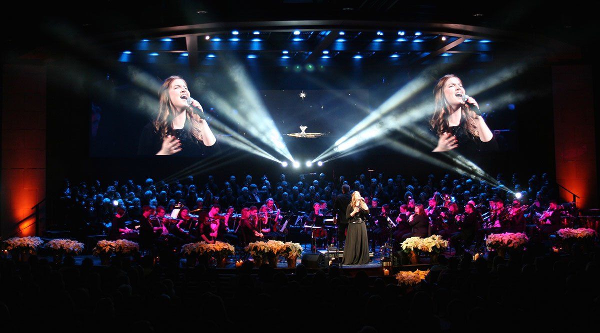 a woman singing on a stage with an orchestra behind her