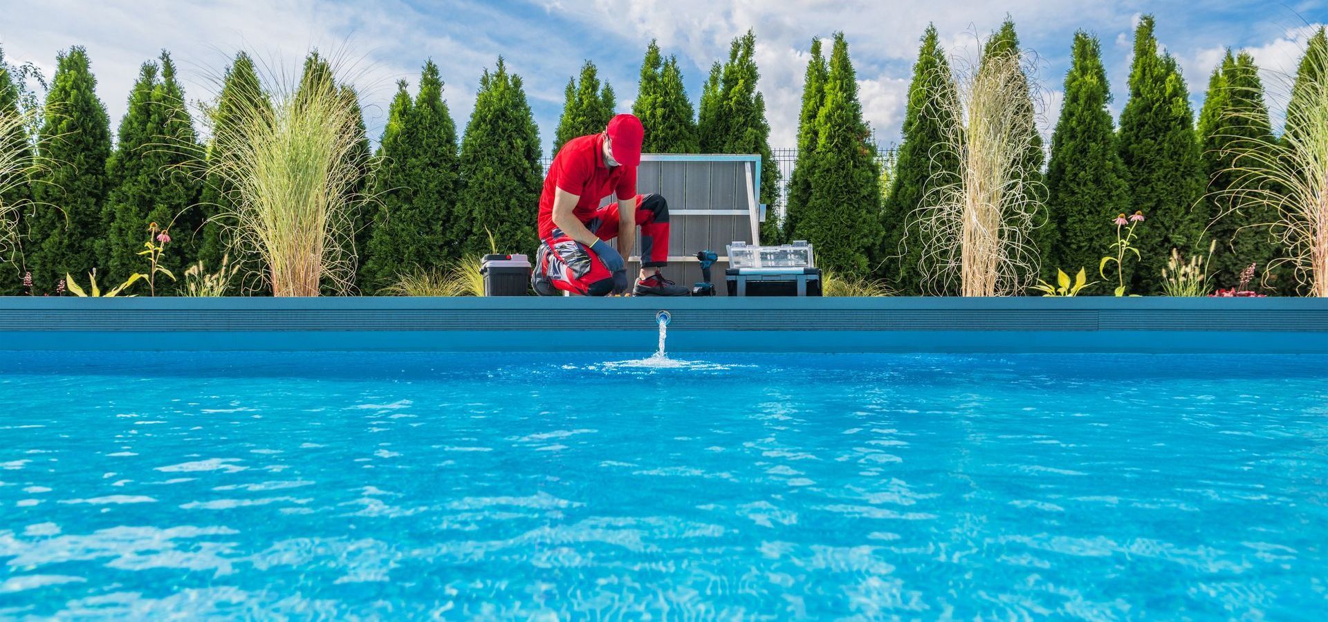 A man in a red suit is working on a swimming pool.