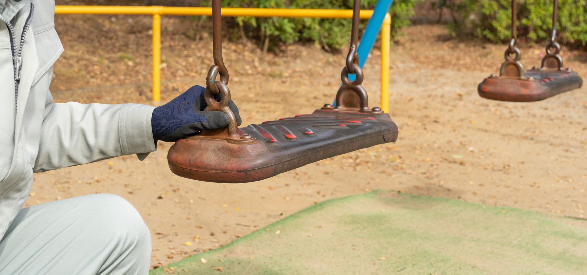 A man is fixing a swing in a park.