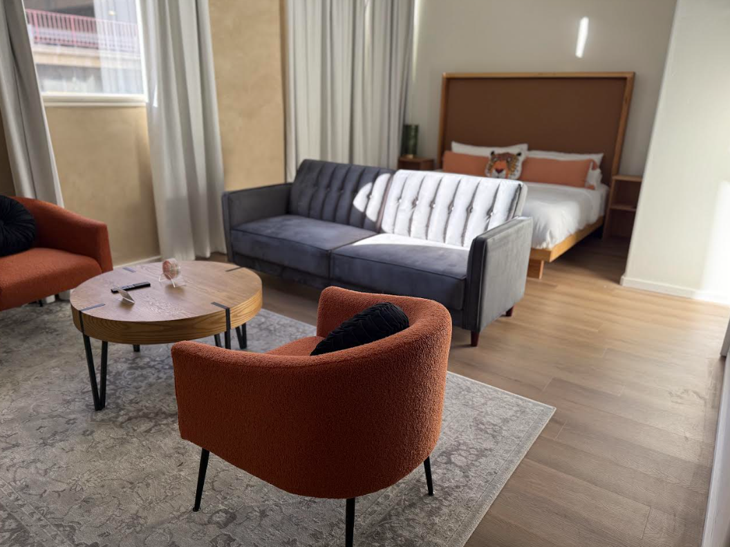 Bedroom with a bed, pillows, a rolled towel, and window with curtains.