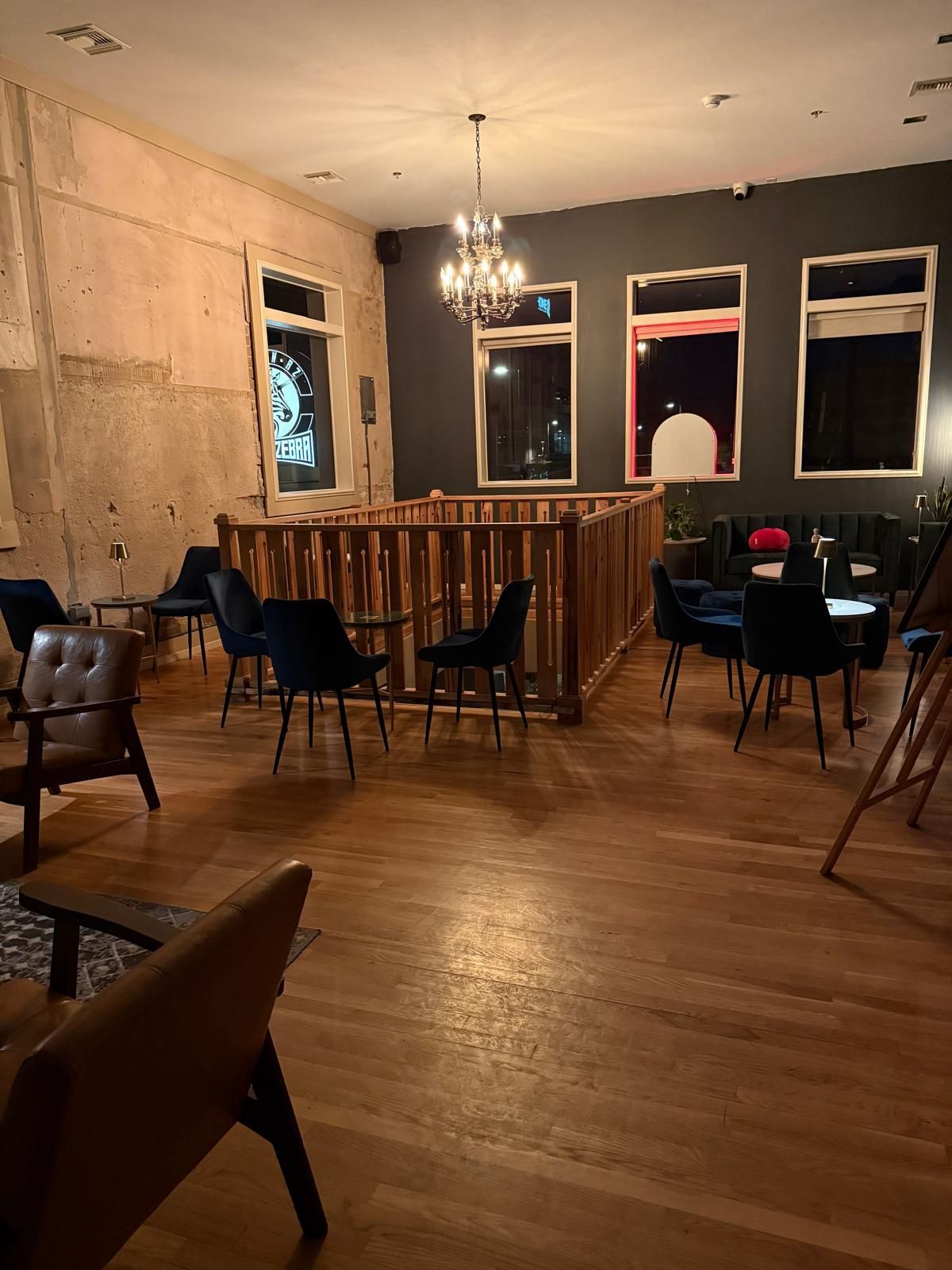Interior of a dimly lit restaurant or bar with wooden floors, dark walls, and seating areas.
