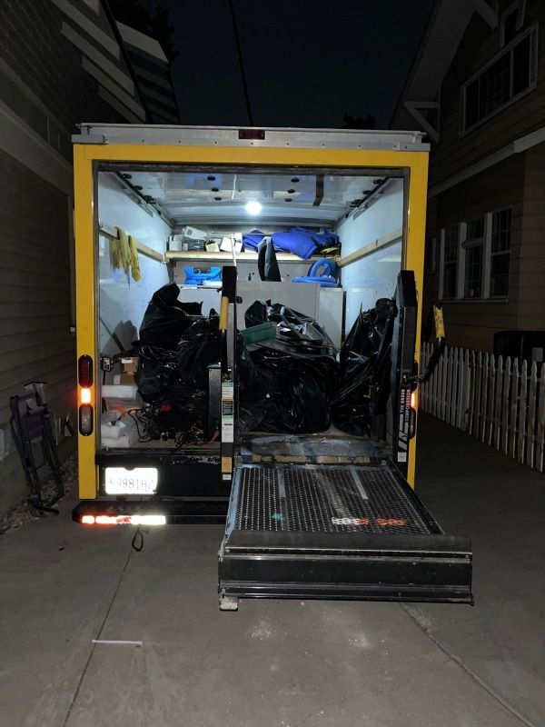 A yellow van with a lift on the back is parked in a driveway