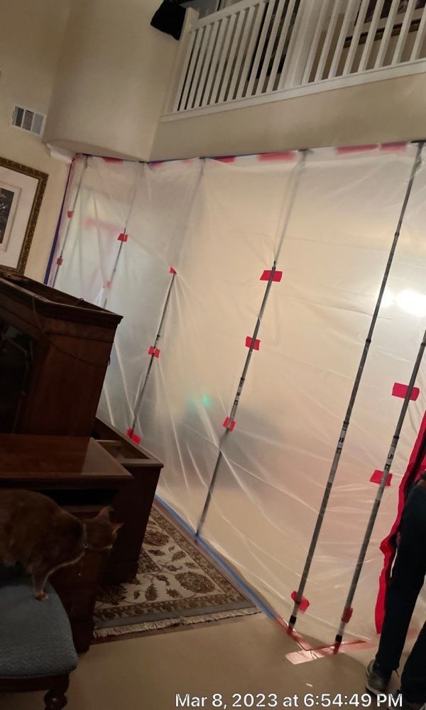 A living room with a lot of plastic covering the walls.