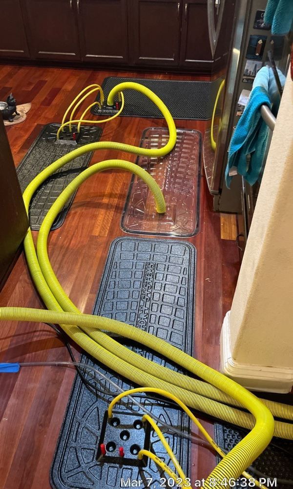 A bunch of yellow hoses are laying on the floor in a kitchen.