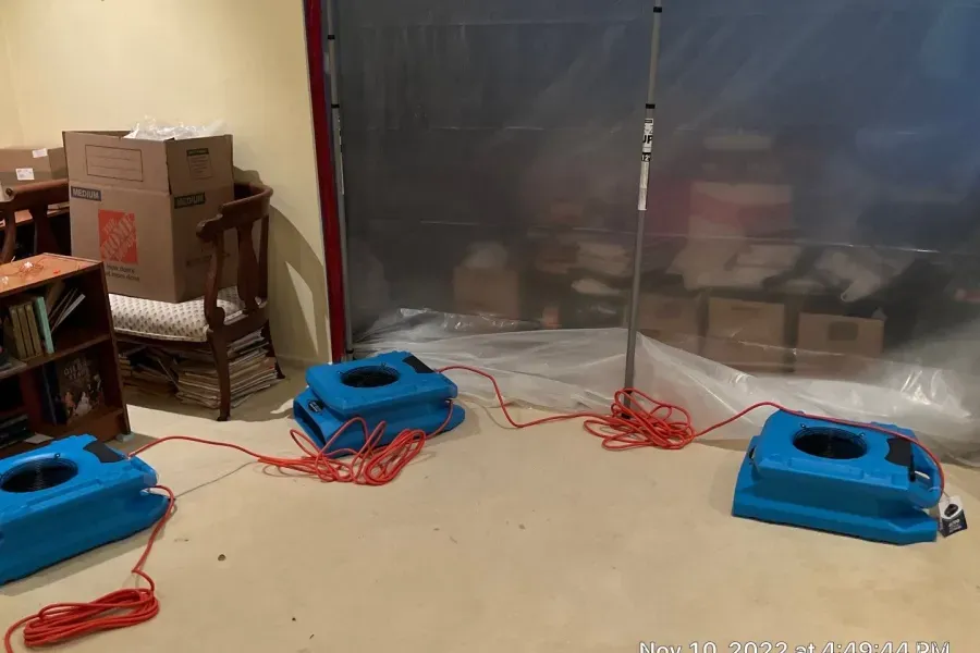 A room with boxes on the floor and a tarp on the wall.