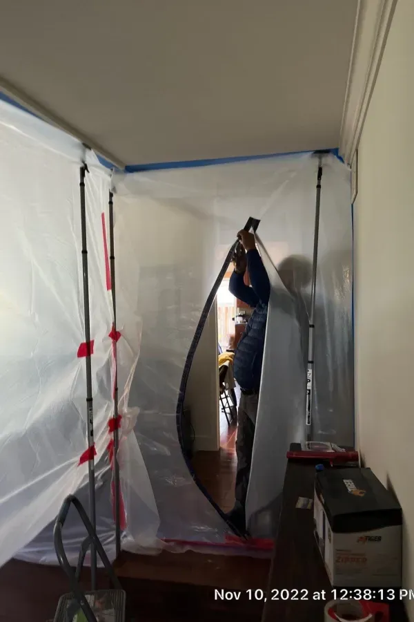 A man is standing in a room covered in plastic.
