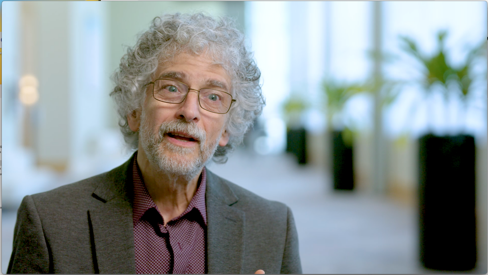 A mature man with gray curly hair and wire rimmed glasses is looking at the camera with a surprised face