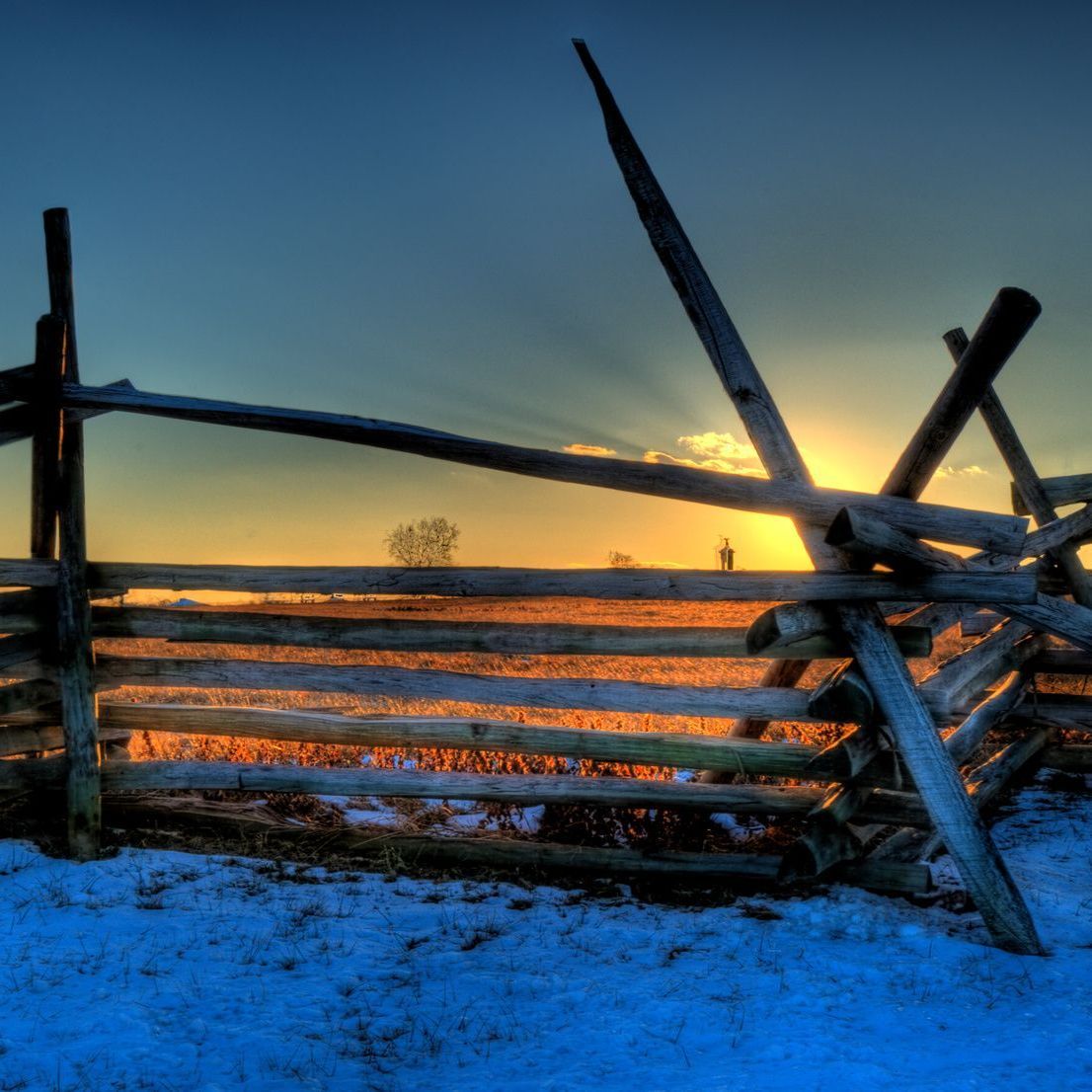 A wooden fence with a sunset in the background