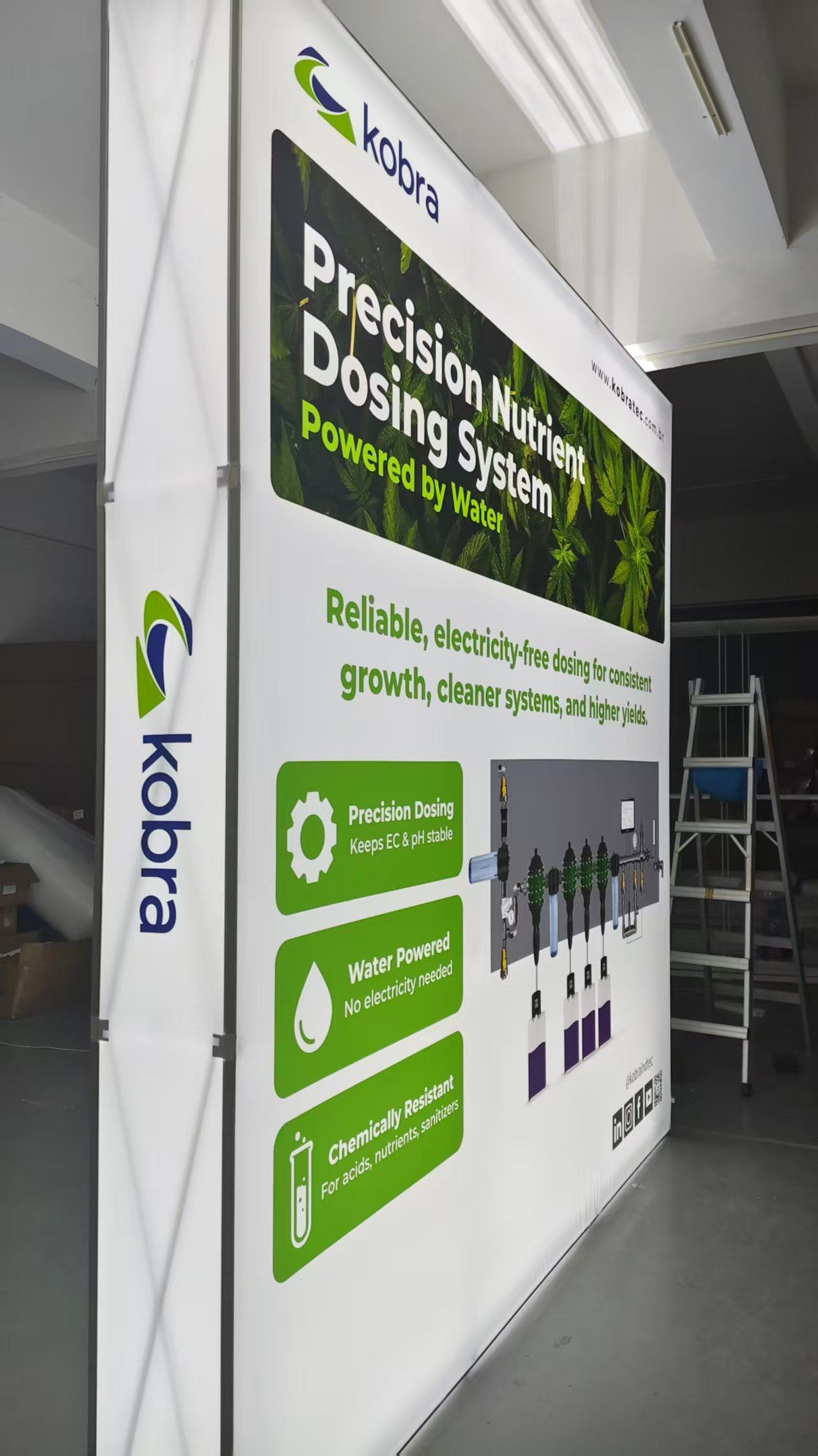 Large 8'x8' banner with green and white graphics, illuminated from inside, and a ladder in the background.