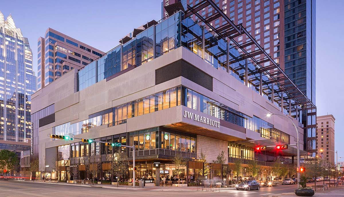 A large building with a lot of windows is sitting on the corner of a city street.