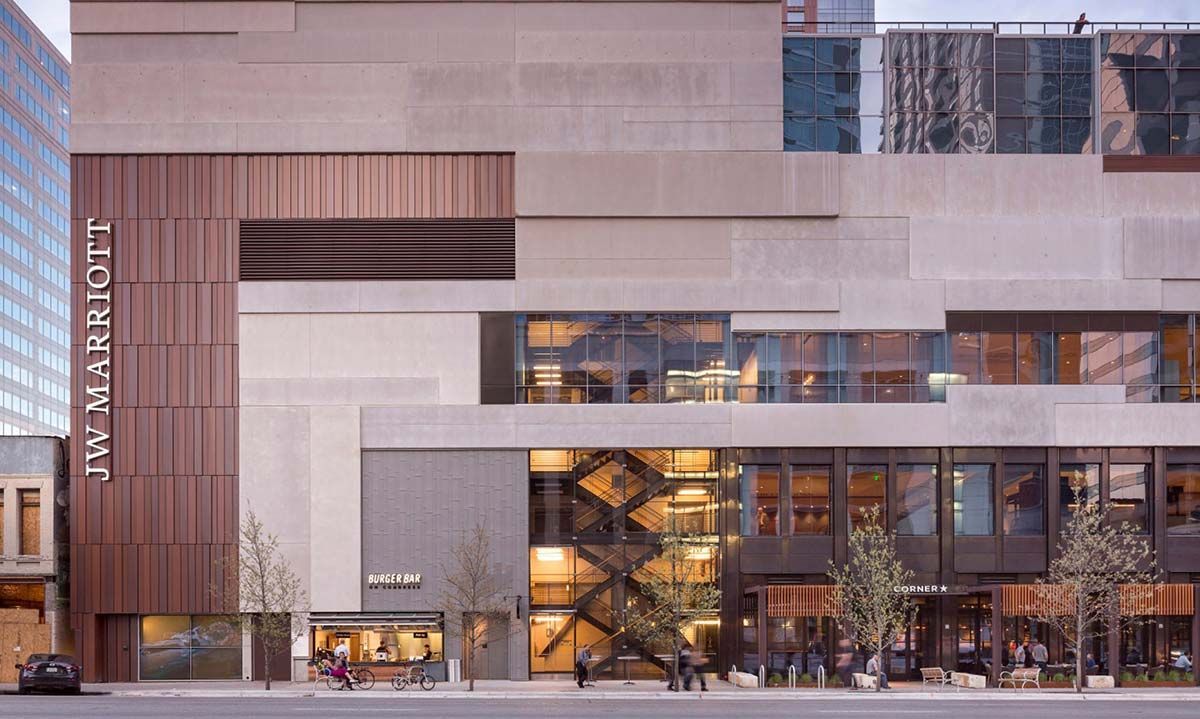 A photo of the JW Marriott Austin, a building with multiple textures - bronze, glass and stone, reflecting images of the city. 