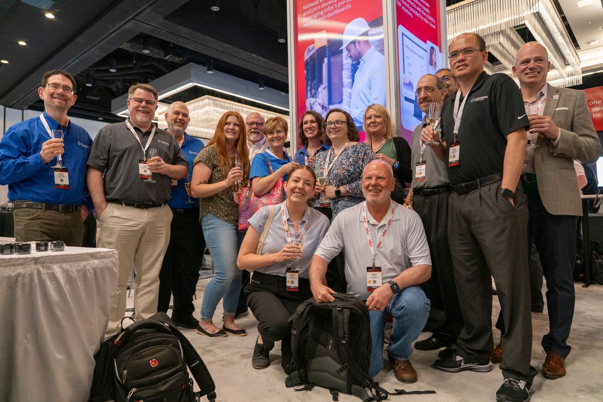 A large group of TUG Attendees wearing blue jeans, slacks and khaki pants with button down shirts and blouses and name badges on Infor lanyards posing for a picture.