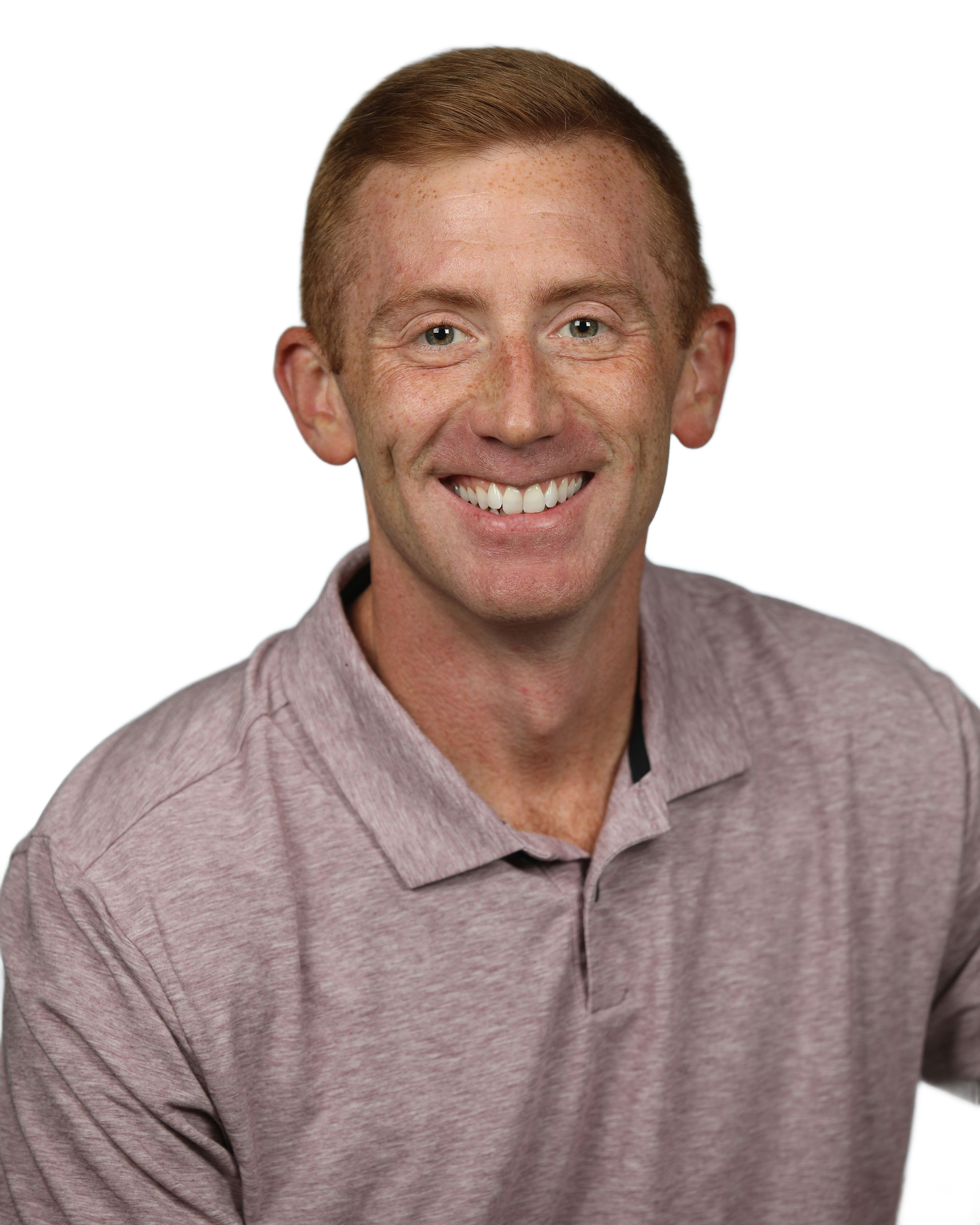 Man with short, reddish-brown hair smiling at the camera, wearing a pink polo shirt.