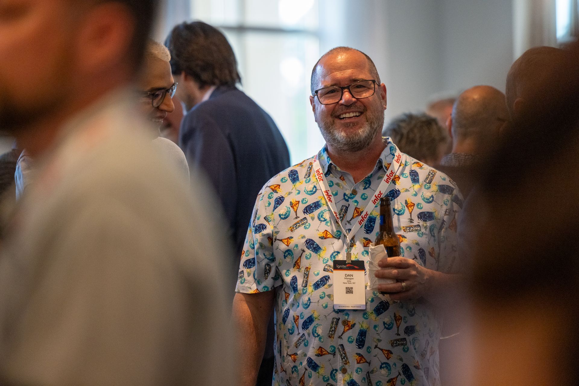 A man (Dan Mangen) wearing a tropical print shirt smiles at the camera