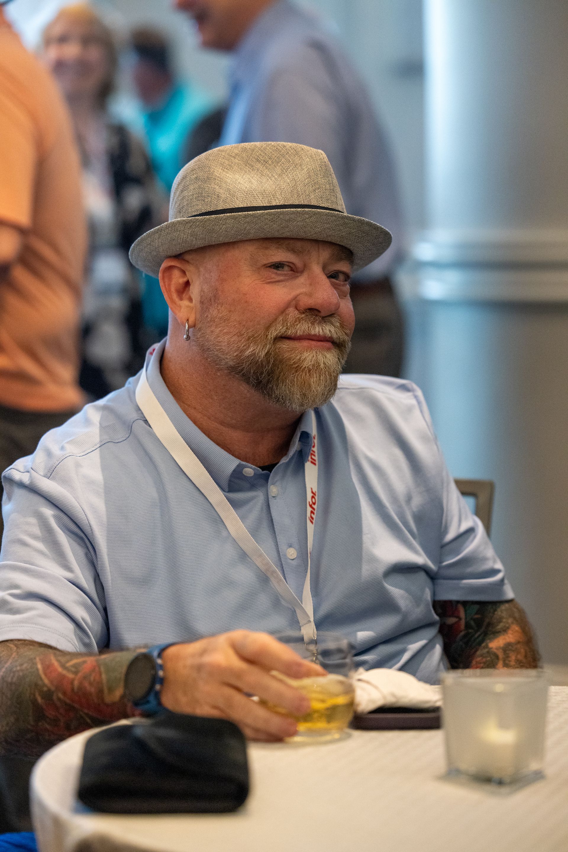 A man wearing a hat grins at the camera
