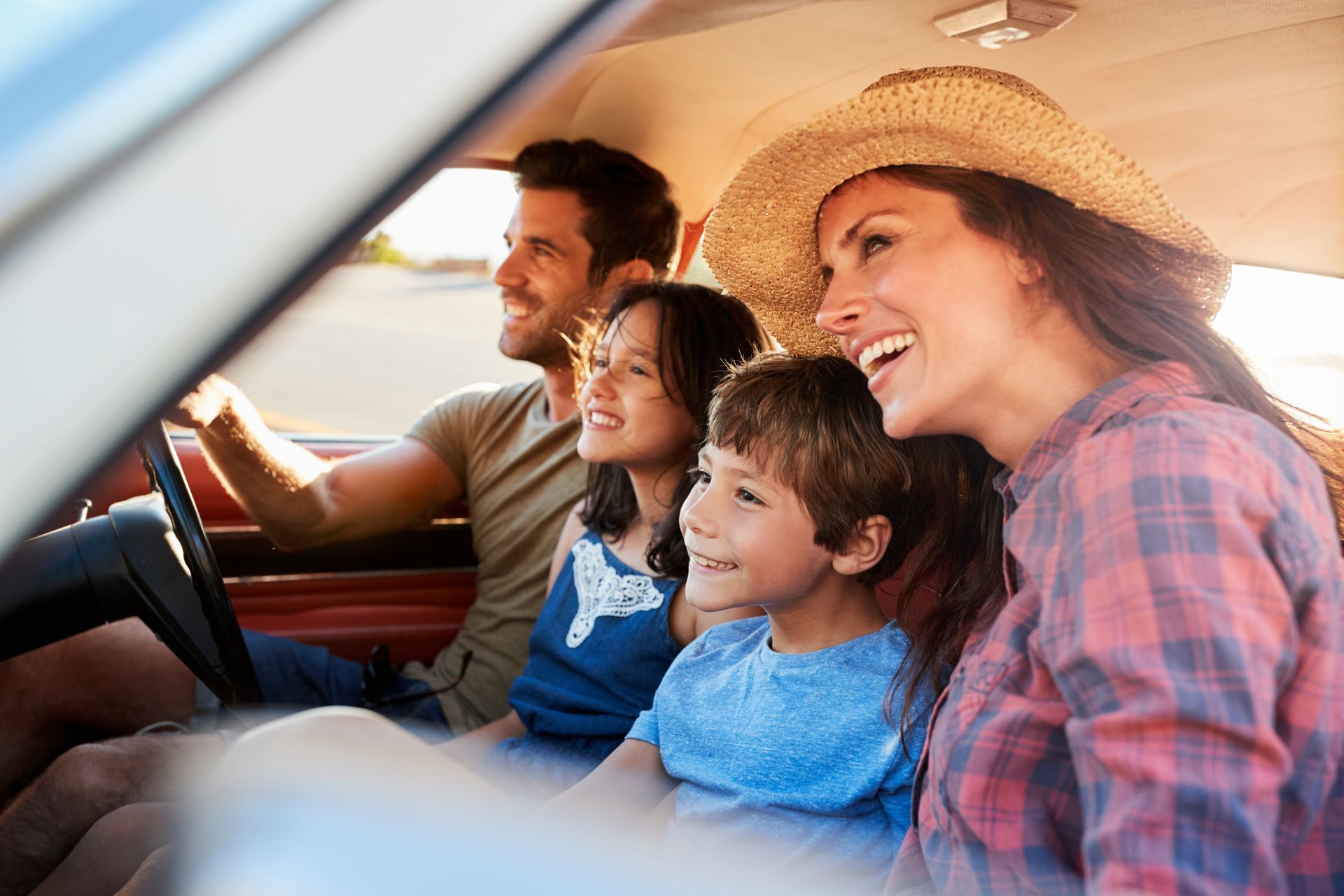 A family is sitting in the back seat of a car.