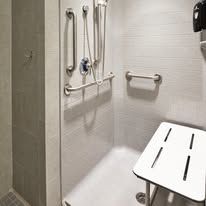 A bathroom with a bathtub , shower , and a stool.