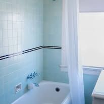 Light blue bathroom with a bathtub, white shower curtain, and a window.