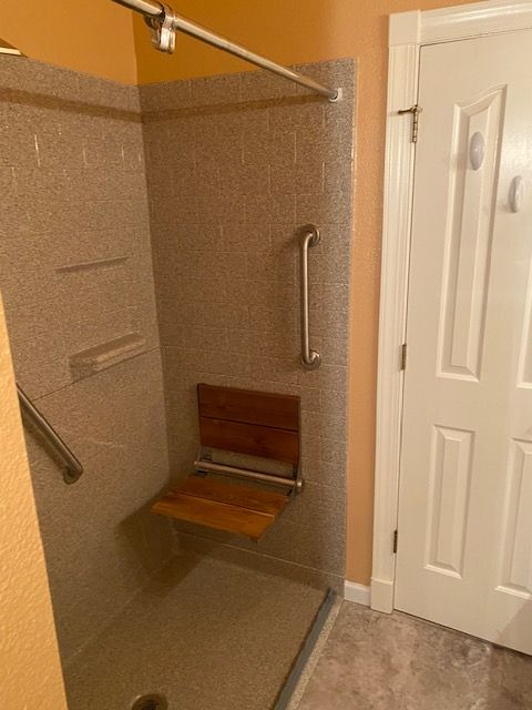 A bathroom with a walk in shower with a wooden seat.