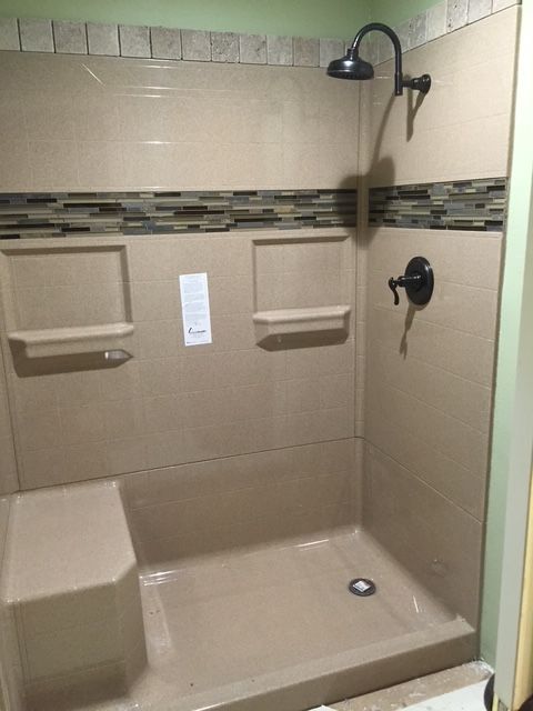 A shower stall with a shower head and shelves in a bathroom.