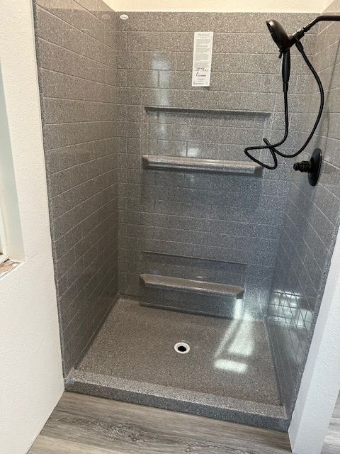 A shower stall with a shower head and shelves in a bathroom.