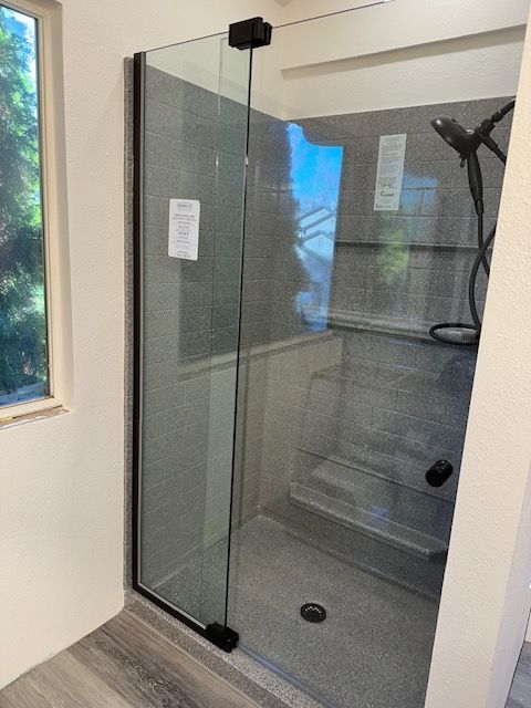 A bathroom with a walk in shower and a window.