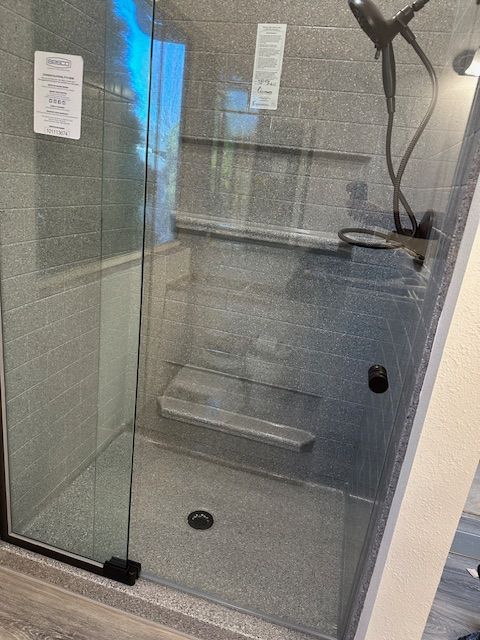 A bathroom with a walk in shower with a glass door.