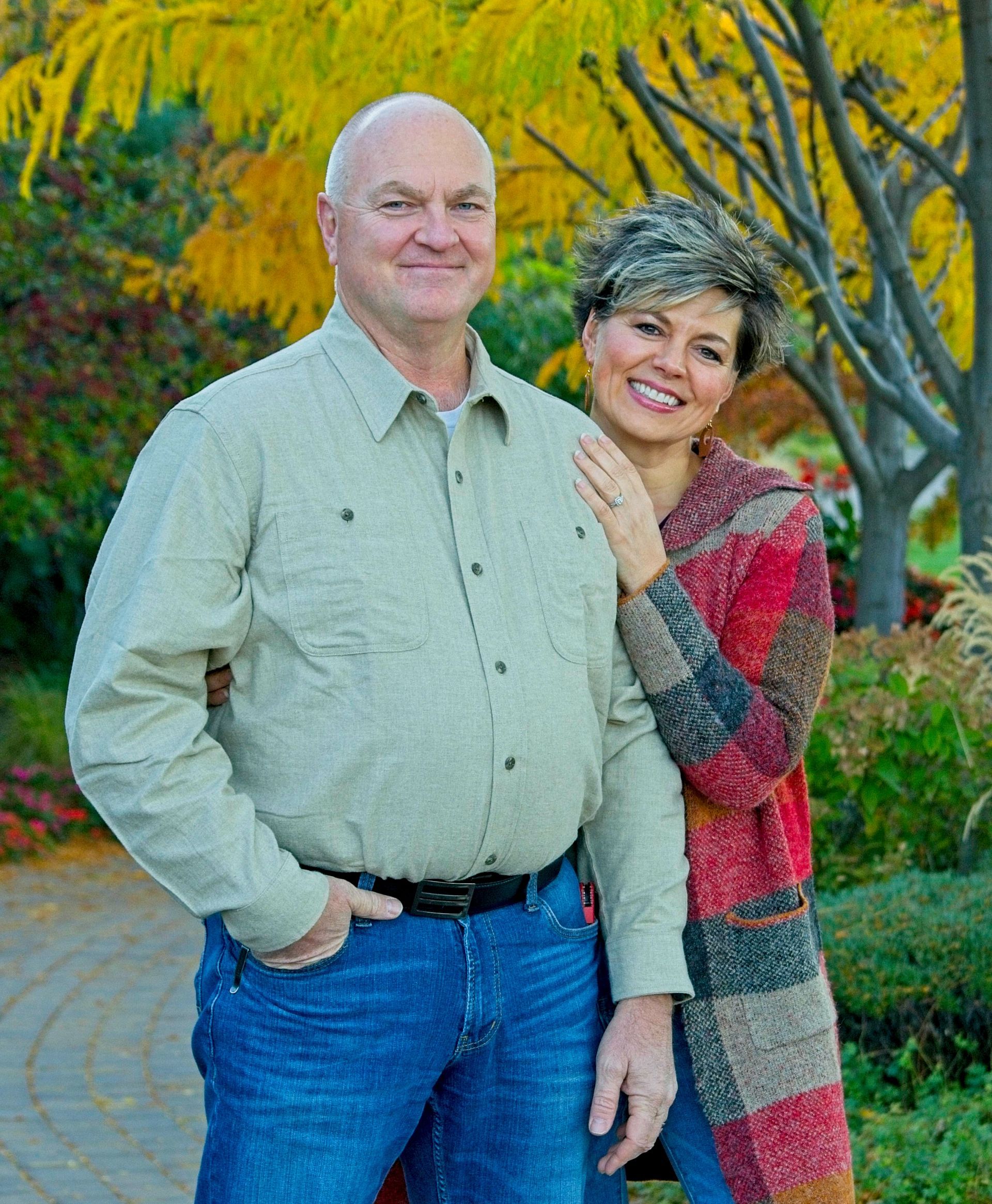 A man and a woman are posing for a picture in a park.