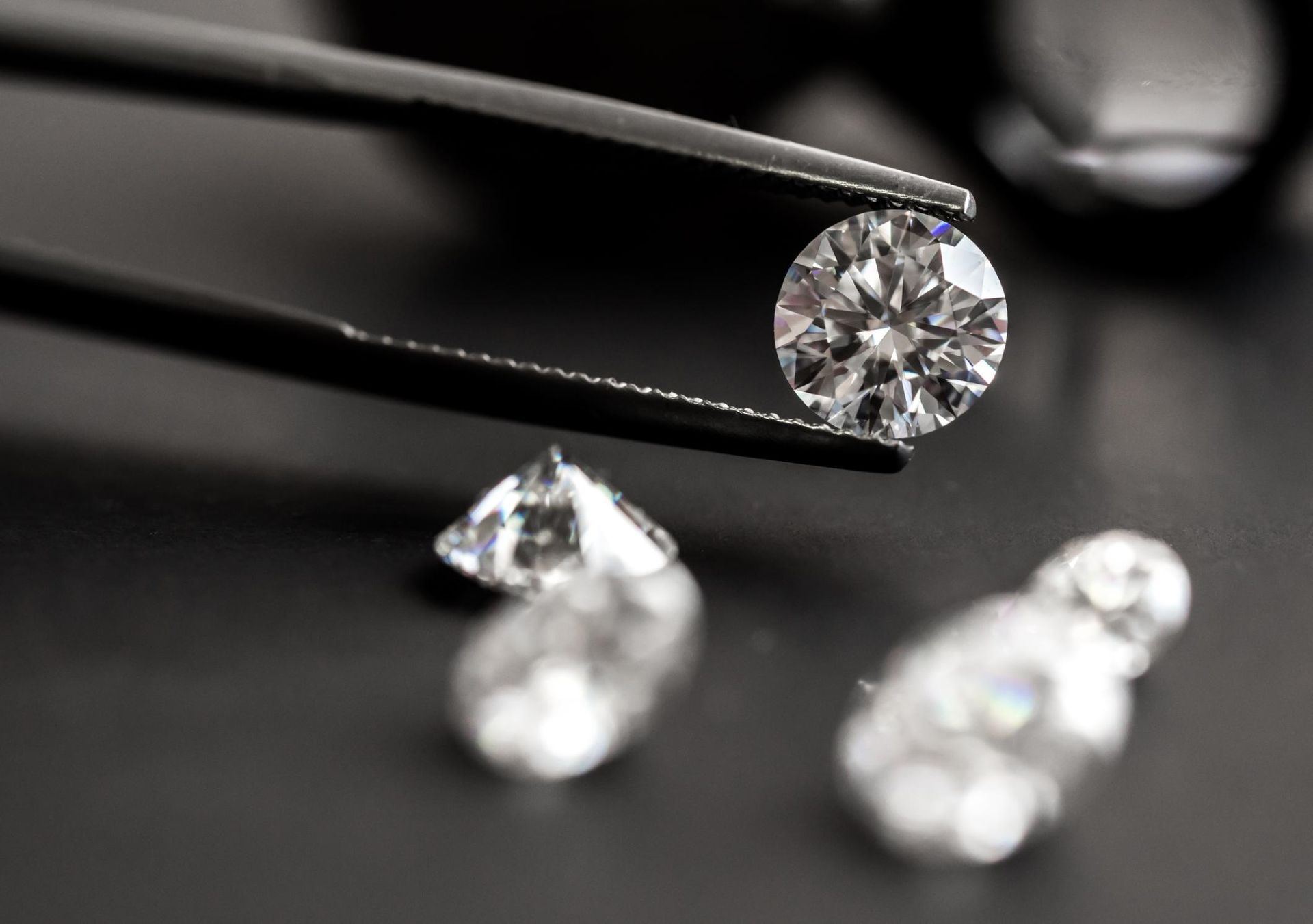 A close up of a pair of tweezers holding a diamond.