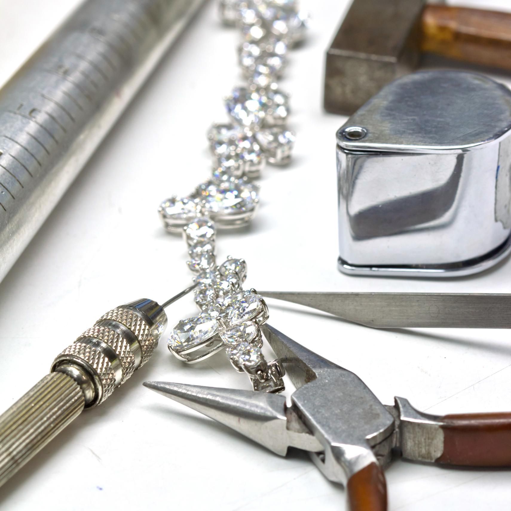 A necklace is being worked on with a pair of pliers.