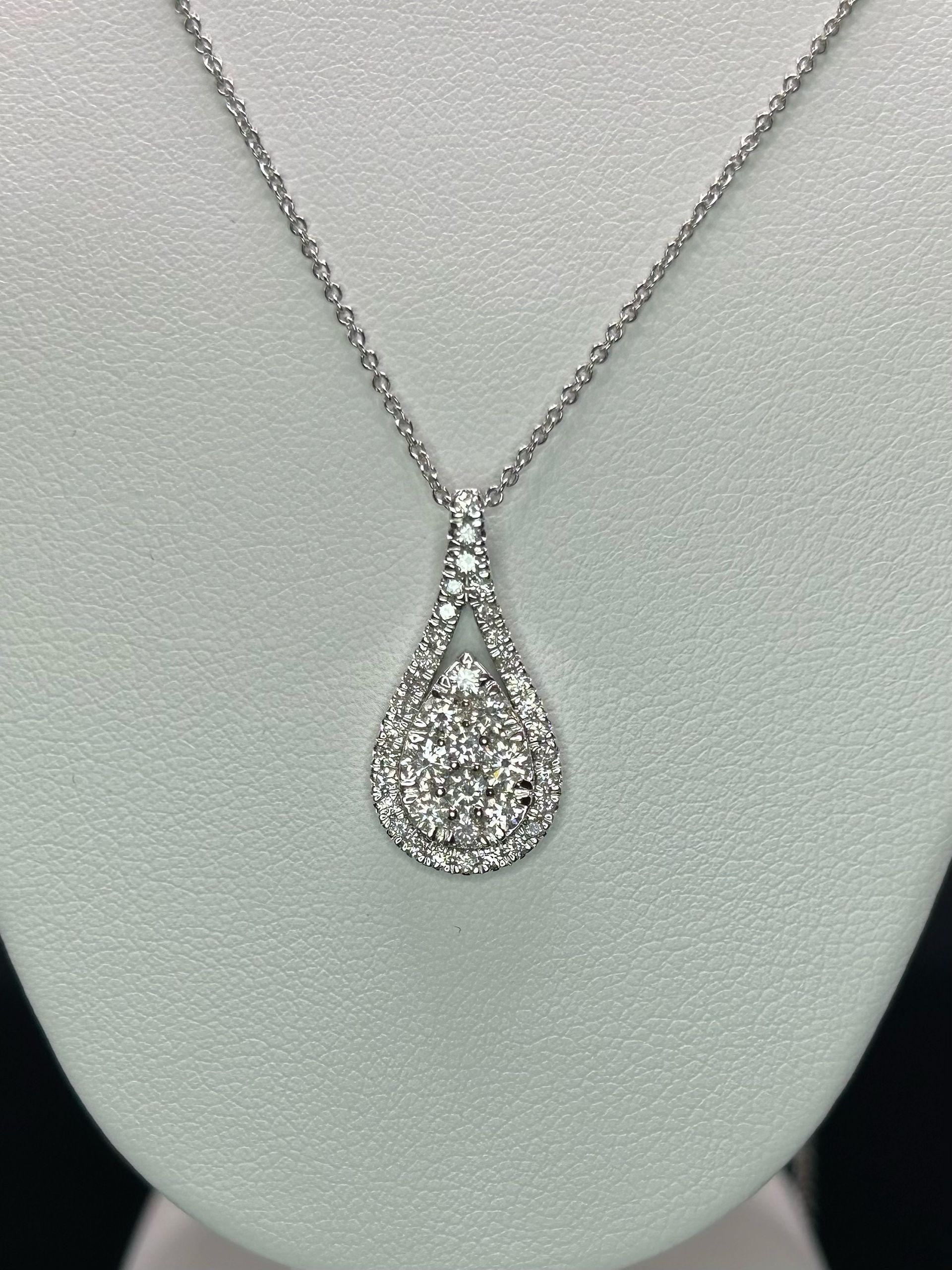 A white gold necklace with a diamond pendant on a mannequin.