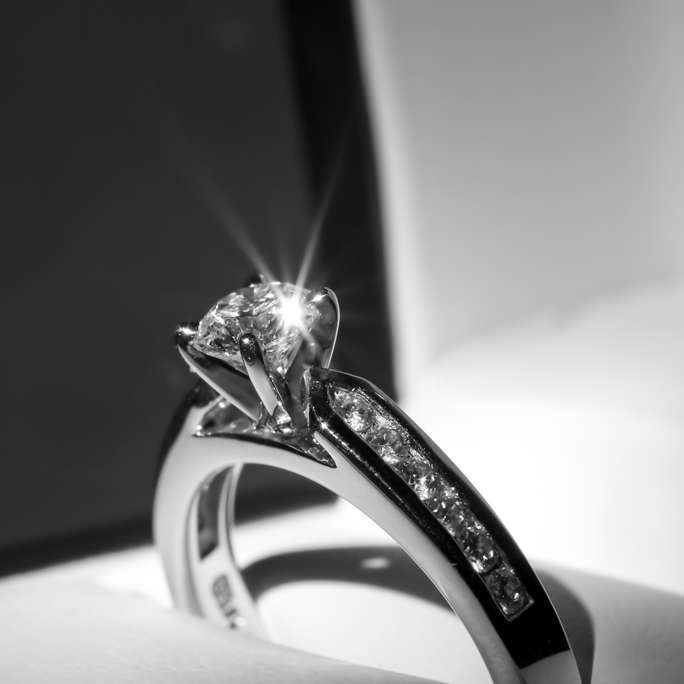A black and white photo of a diamond ring in a box.