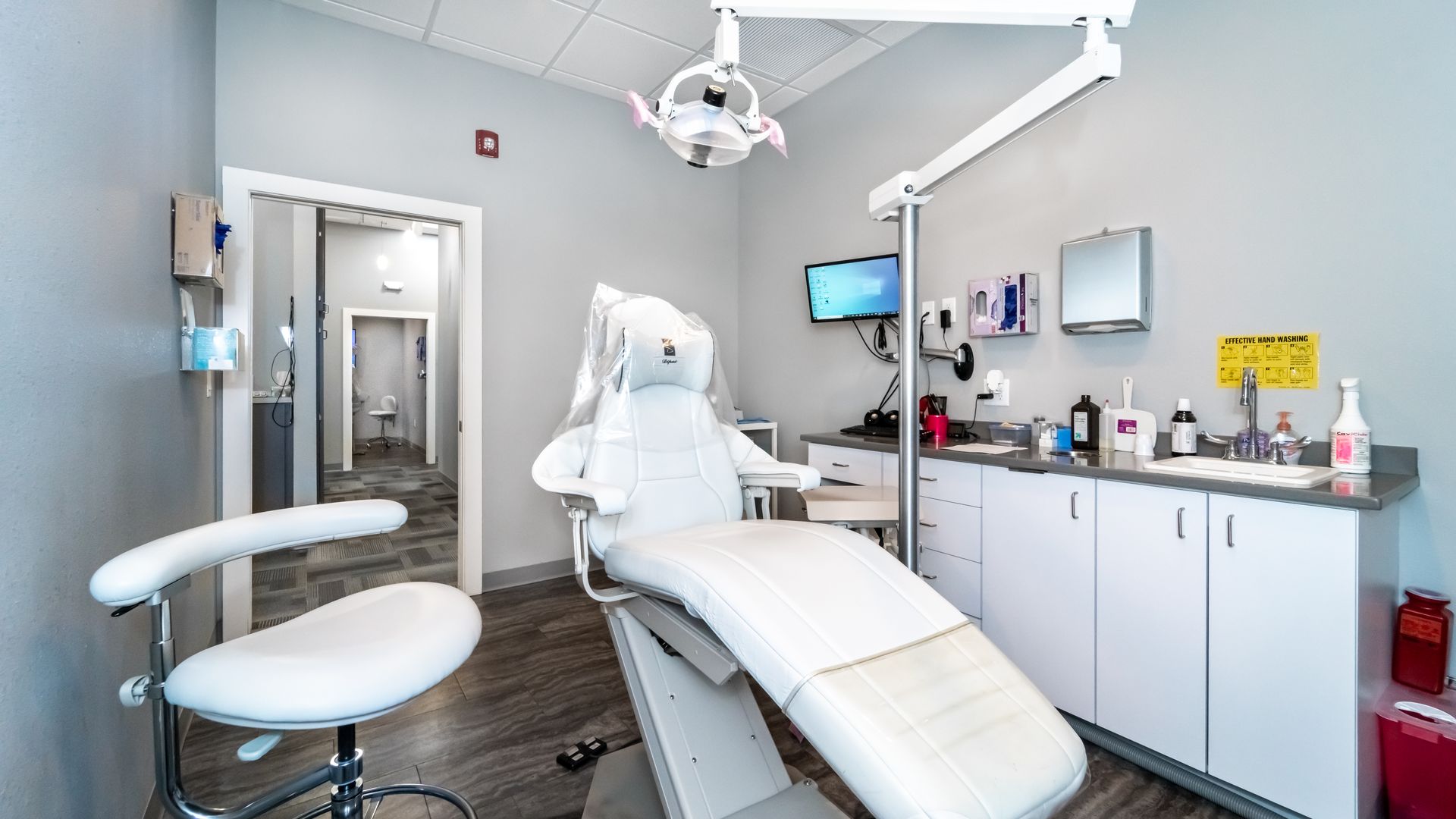 A dental office with a dental chair and a sink.