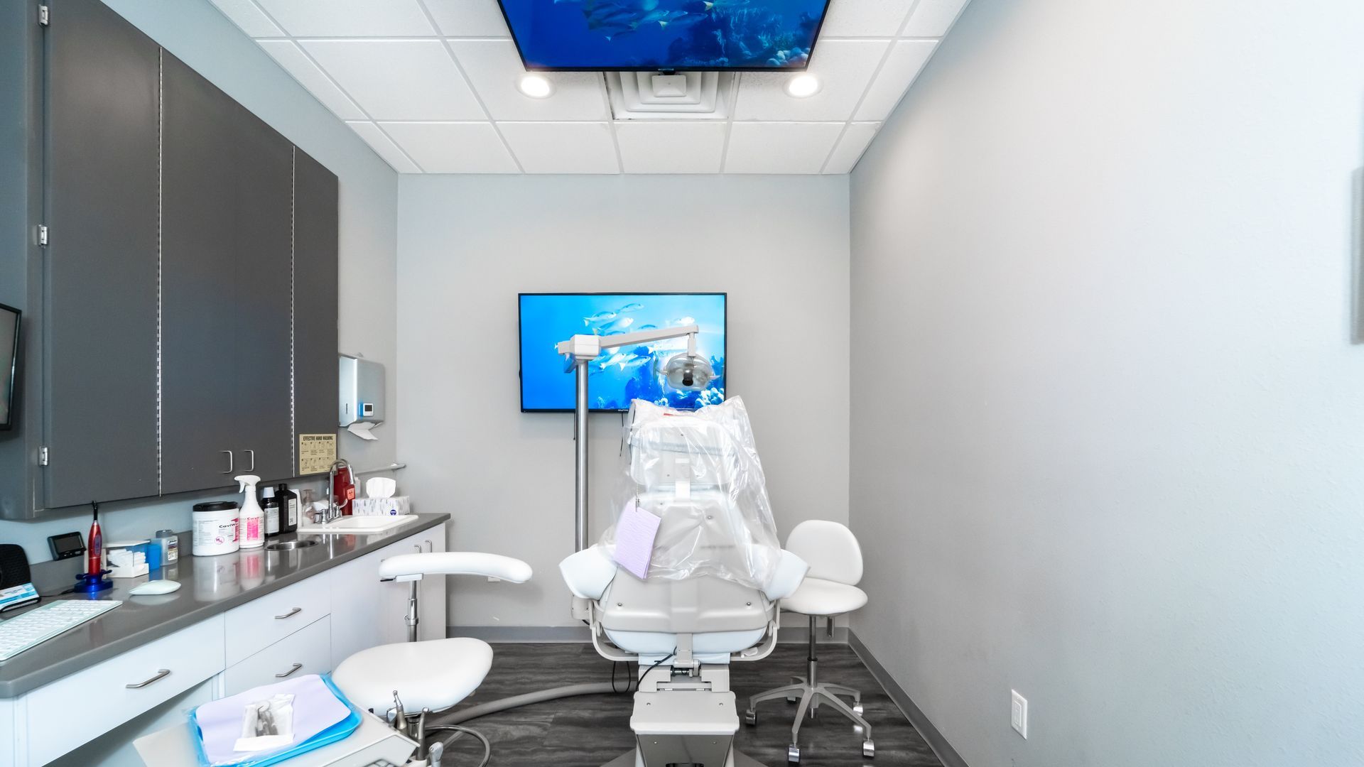A dental office with a dental chair and a television on the wall.