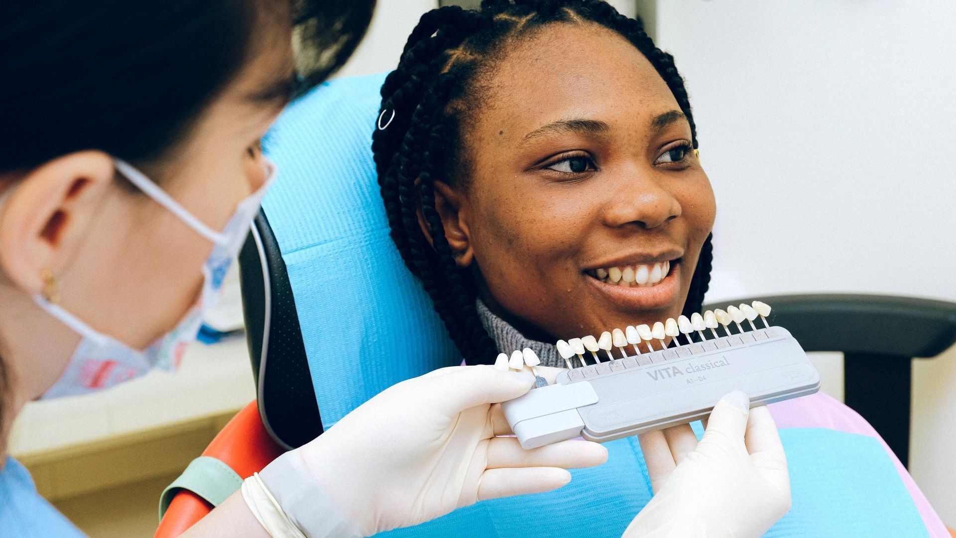 A woman is sitting in a dental chair while a dentist examines her teeth.