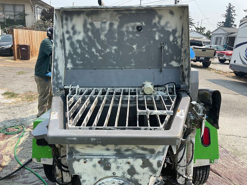 A man is standing next to a concrete mixer on a trailer.