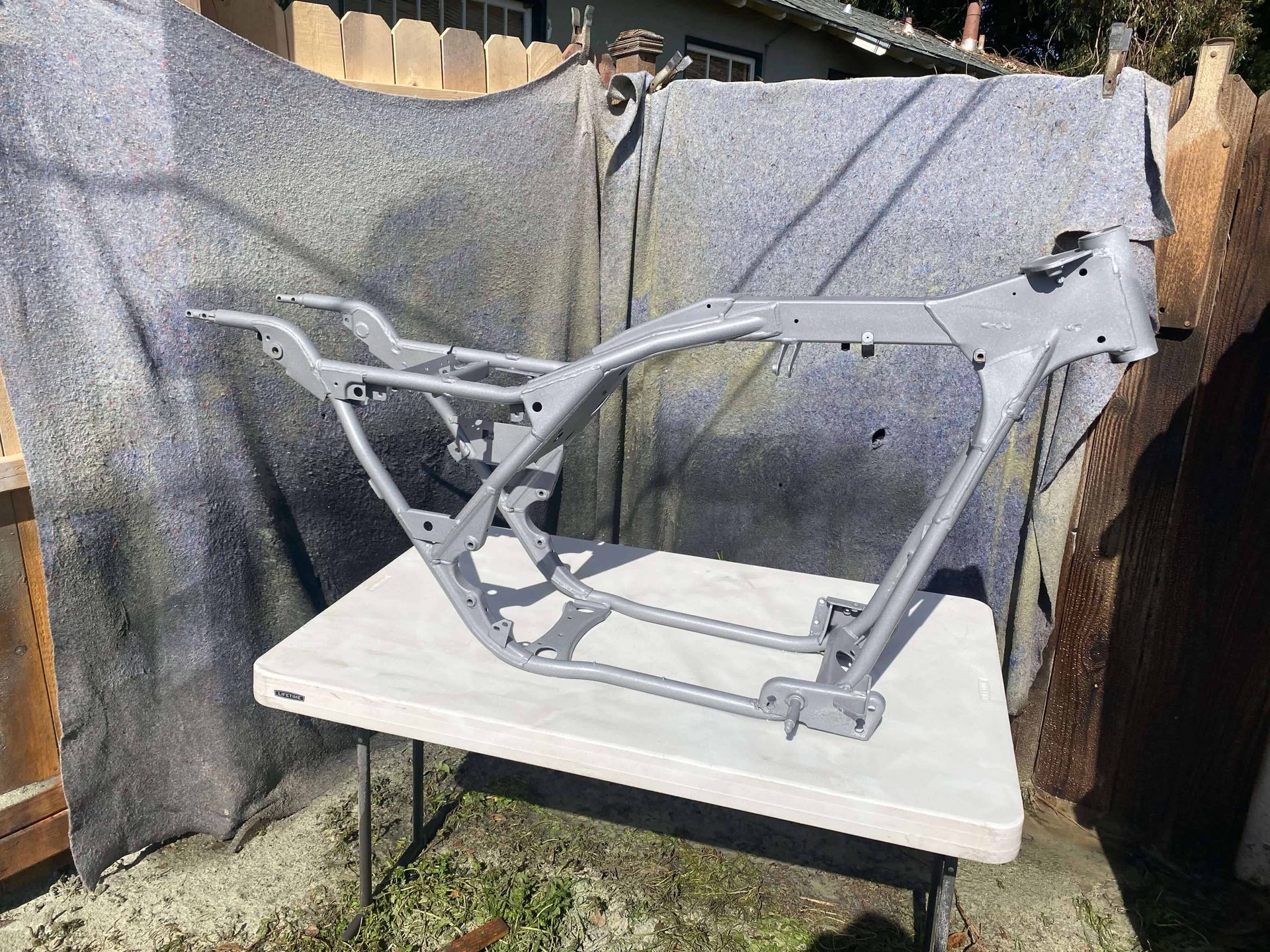 A motorcycle frame is sitting on top of a white plastic table.