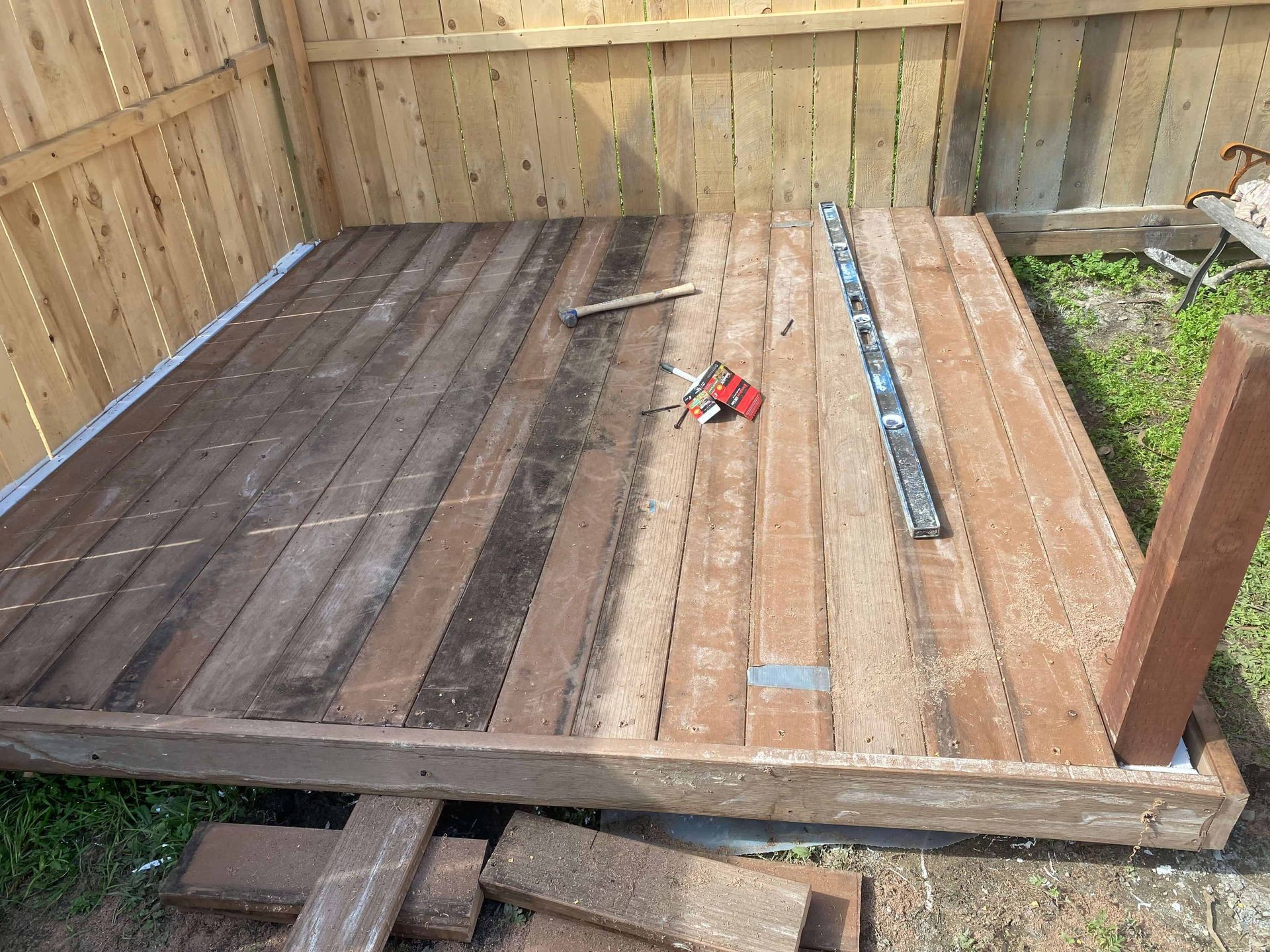 A wooden deck is being built next to a wooden fence.