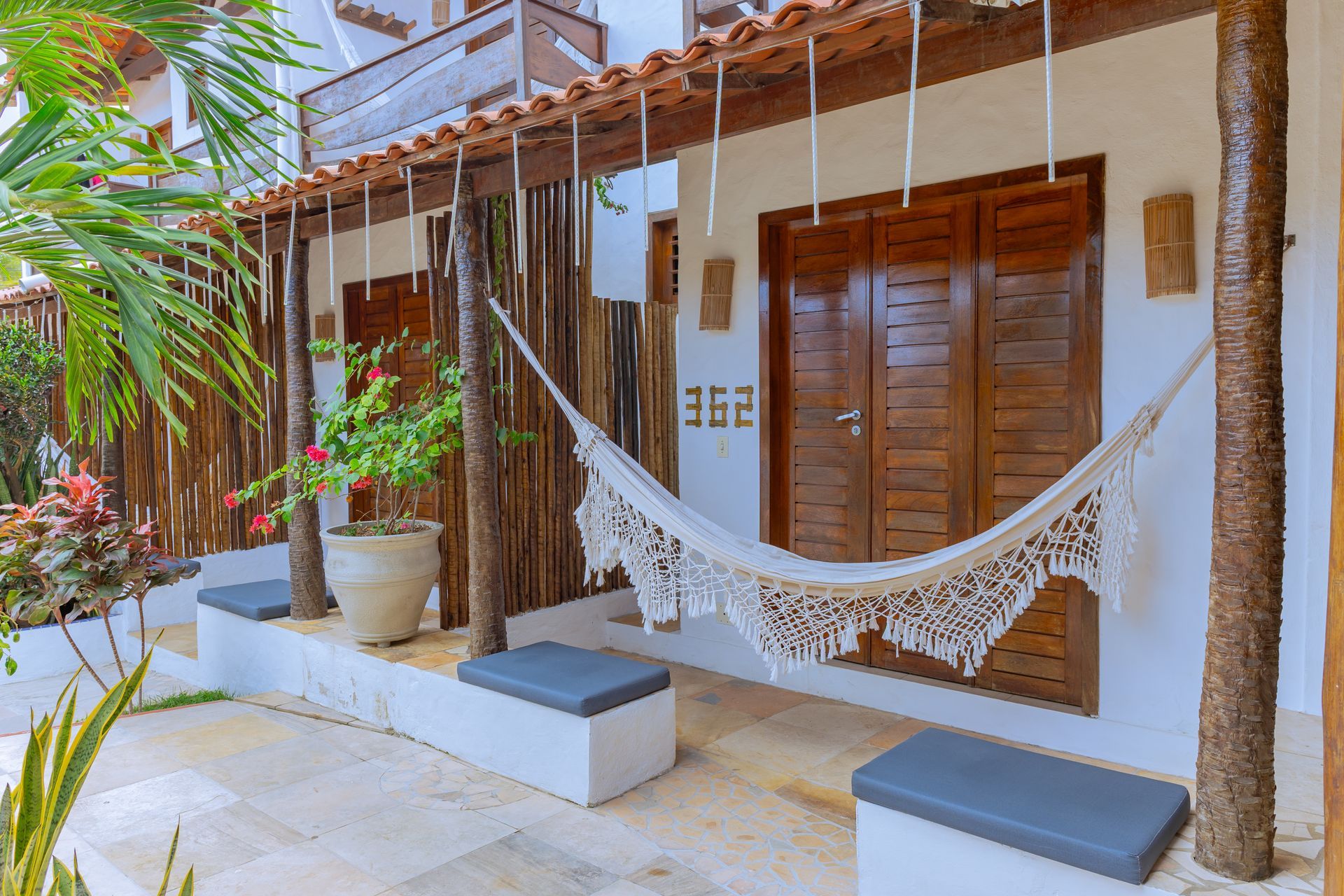 Piscina com uma boia amarela, água azul e uma palmeira em silhueta contra o sol ao pôr do sol.