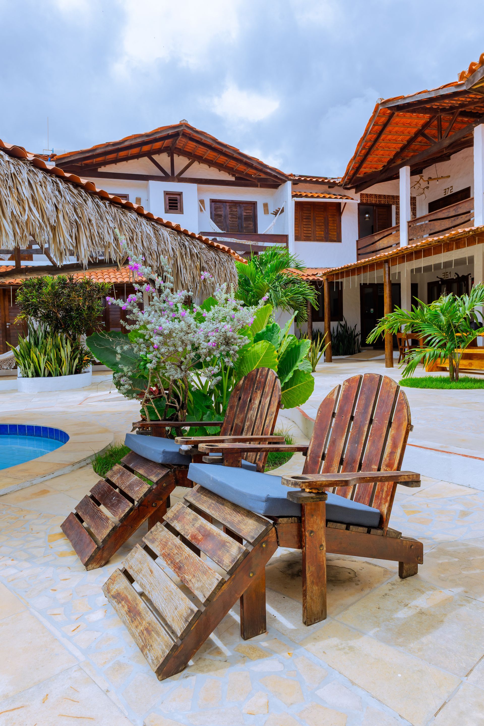 Portão branco que dá acesso a uma área gramada com cavalos e uma placa com a inscrição 